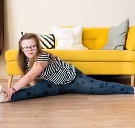 teenager girl with Down syndrome sitting on twine on the floor at home