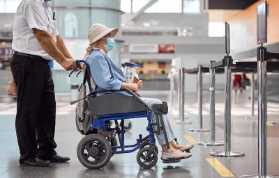 Airport worker rolling a wheelchair with a senior woman