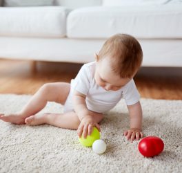 baby playing with balls on floor at home