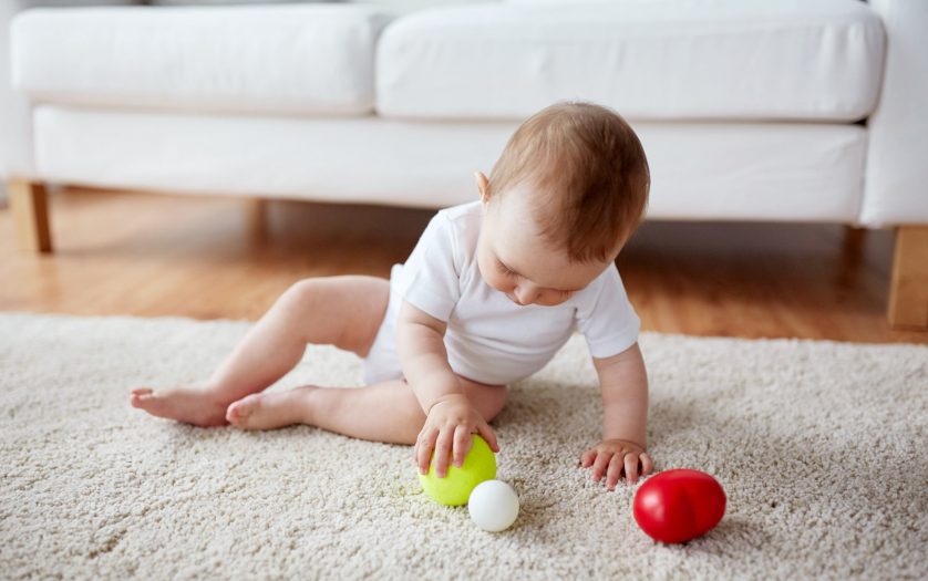 baby playing with balls on floor at home