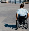 back view of man in sunglasses using wheelchair on street