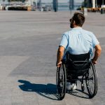 back view of man in sunglasses using wheelchair on street