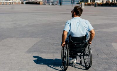 back view of man in sunglasses using wheelchair on street
