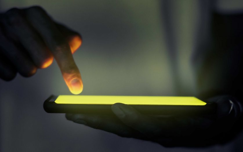 Hand touching illuminated smartphone screen