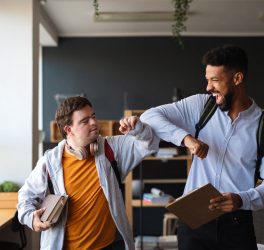 Young happy man with Down syndrome with his mentoring friend celebrating success