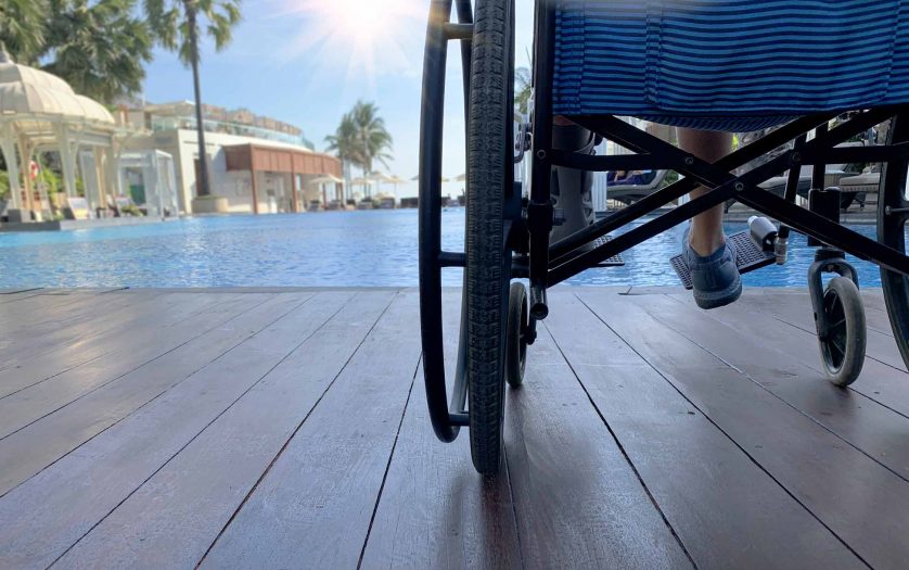 Woman sits on wheelchair next to swimming pool