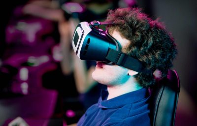 Side view of young gamer playing videogame in virtual reality goggles