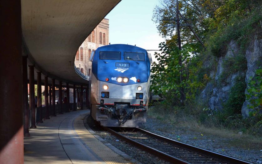 An Amtrak passenger train pulling into the station with an outdoor platform