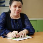 blind woman hands writing braille by using slate and stylus tools