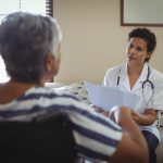 Female doctor interacting with senior woman on wheelchair