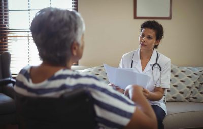 Female doctor interacting with senior woman on wheelchair