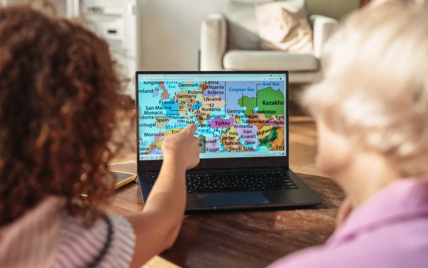 A Person Pointing at a Map on a Laptop.