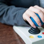 Woman with cerebral palsy works on a specialized computer mouse