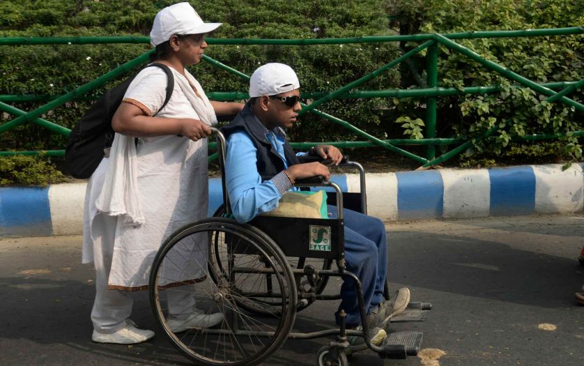woman pushing a person in wheelchair during a rally in Calcutta, India.