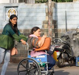 Young woman pushing the wheelchair of a woman