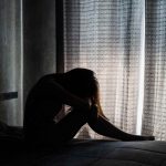 Lonely young woman depressed and stressed sitting in the dark bedroom