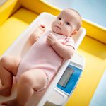 Beautiful newborn baby on weighing scale.