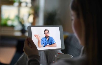 Young woman having video call with doctor on tablet at home