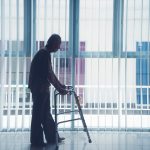 Elderly man walks with a walker near the window