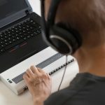 blind person hands using computer with braille display