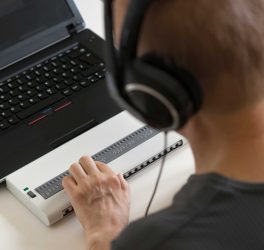 blind person hands using computer with braille display