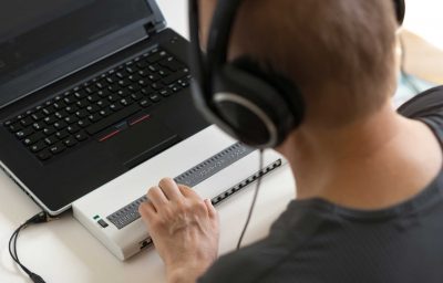 blind person hands using computer with braille display