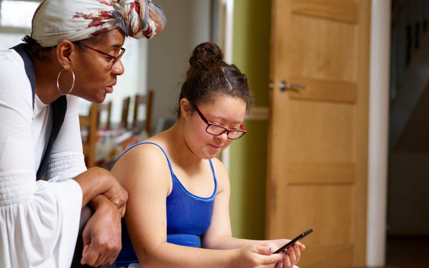 Mother with daughter with Down Syndrome looking at smart phone at home