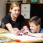 female teacher sitting at desk with a Down syndrome schoolboy