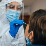 Close up of female health Professional in PPE introducing a nasal swab to a female patient at her house