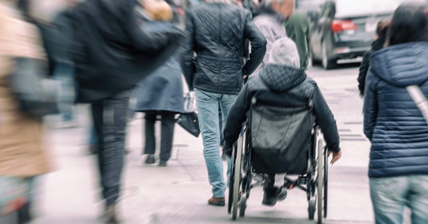 man in a wheelchair on a busy street