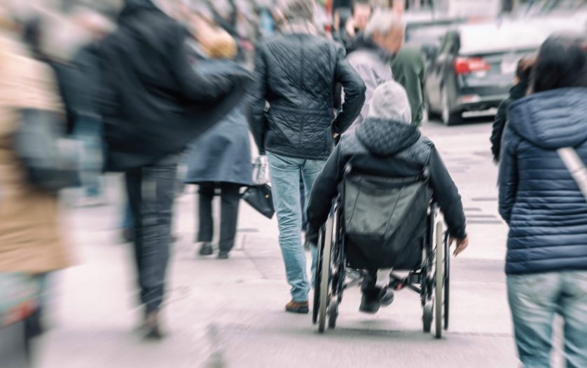 man in a wheelchair on a busy street