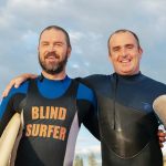 blind surfer with trainer