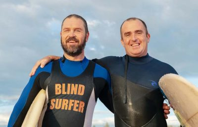 blind surfer with trainer