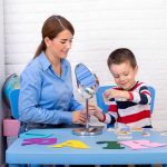 boy in child occupational therapy session doing sensory playful exercises with her therapist.