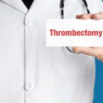 Doctor in smock holds up Thrombectomy card.