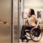 Young businesswoman in wheelchair uses access card to enter the office.