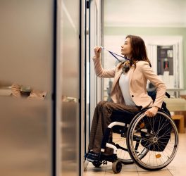Young businesswoman in wheelchair uses access card to enter the office.