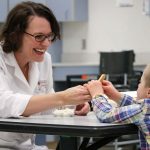 Carolyn Ross works with a child with Down syndrome on the food texture study.