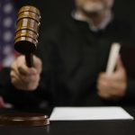 Judge with gavel at wooden table indoors