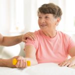 Smiling elderly woman holding dumbbell