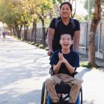 Child in wheelchair with his aunt outdoor.