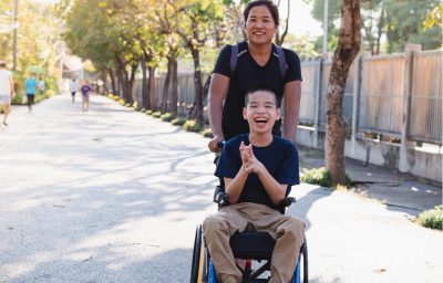 Child in wheelchair with his aunt outdoor.