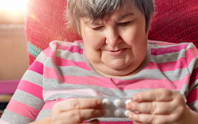 woman with intellectual disability is looking at some of her pills
