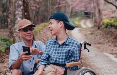 Happy boy with cerebral palsy smiling face with father using mobile phone