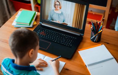 child is sitting at desk learning online