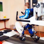 young boy passes robotic therapy in rehabilitation center