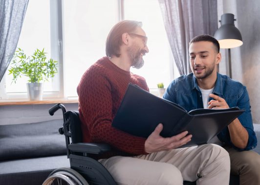 person in wheelchair discussing documents with a person at home