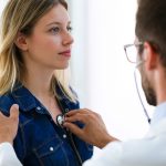 doctor using stethoscope to examine patient.