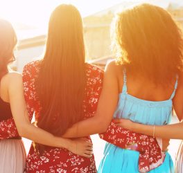 Group of teenagers of different cultures hugging each other at the park at sunset