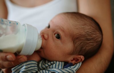 Mother feeding baby with bottle of milk